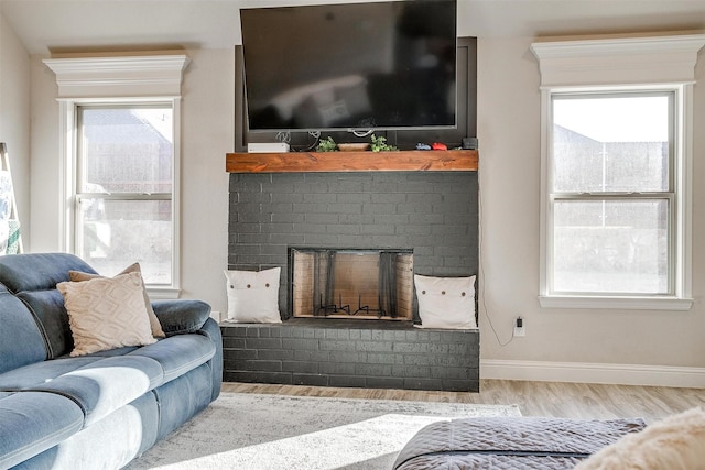 living room featuring a brick fireplace and light hardwood / wood-style floors