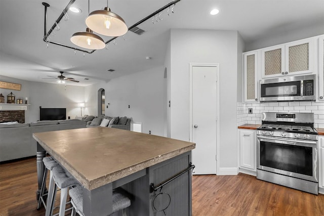 kitchen with decorative backsplash, a kitchen breakfast bar, white cabinetry, and appliances with stainless steel finishes