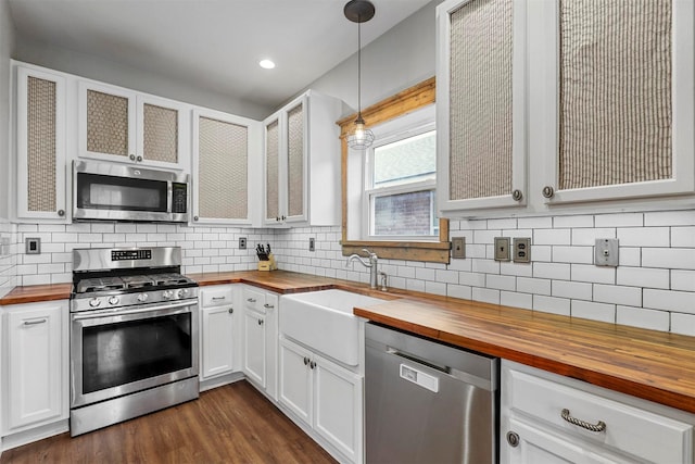 kitchen with white cabinetry, butcher block counters, hanging light fixtures, and appliances with stainless steel finishes