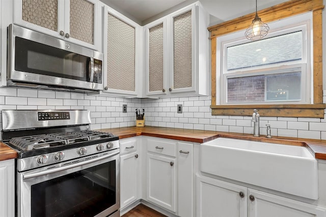 kitchen featuring pendant lighting, white cabinetry, butcher block counters, and appliances with stainless steel finishes