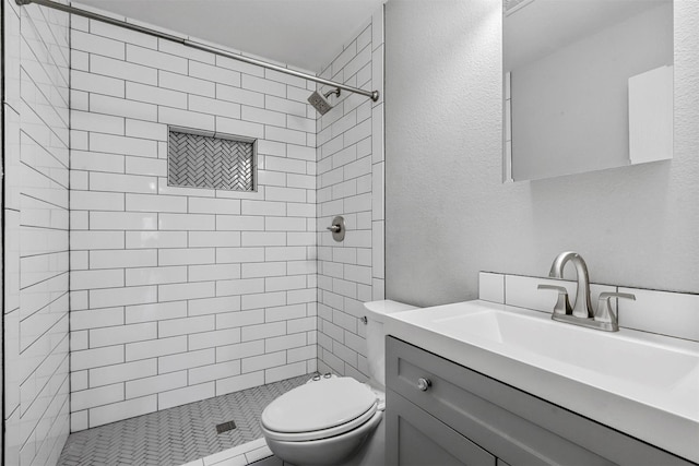 bathroom featuring vanity, toilet, and tiled shower