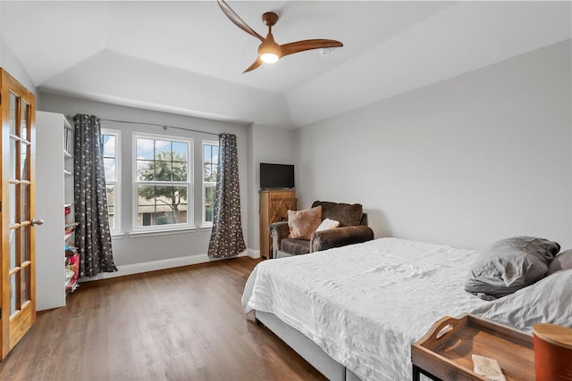 bedroom featuring ceiling fan, lofted ceiling, dark hardwood / wood-style floors, and a tray ceiling