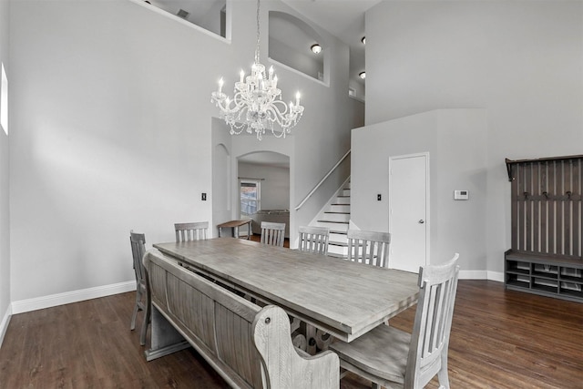 dining area with a high ceiling, dark hardwood / wood-style floors, and an inviting chandelier