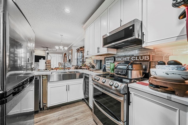 kitchen featuring light hardwood / wood-style floors, appliances with stainless steel finishes, a textured ceiling, decorative backsplash, and white cabinets