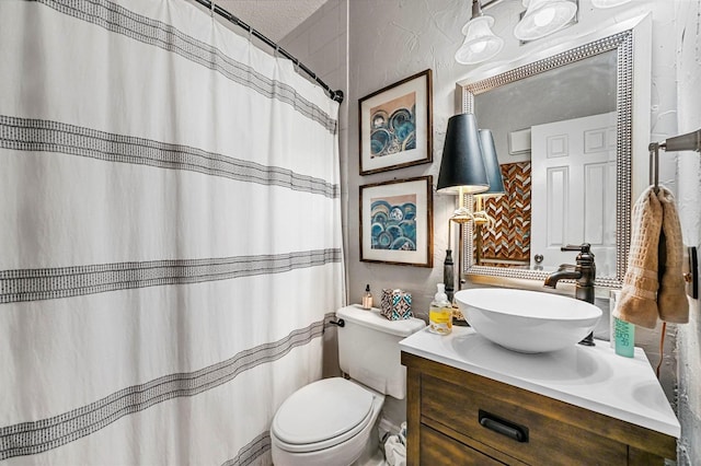 bathroom with a textured ceiling, toilet, and vanity