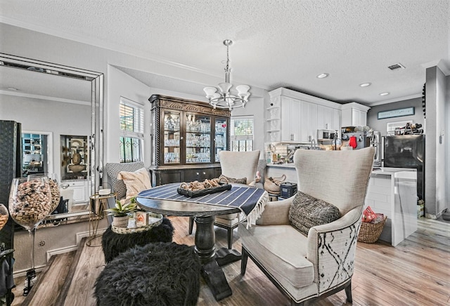 dining area with crown molding, a textured ceiling, and light hardwood / wood-style flooring