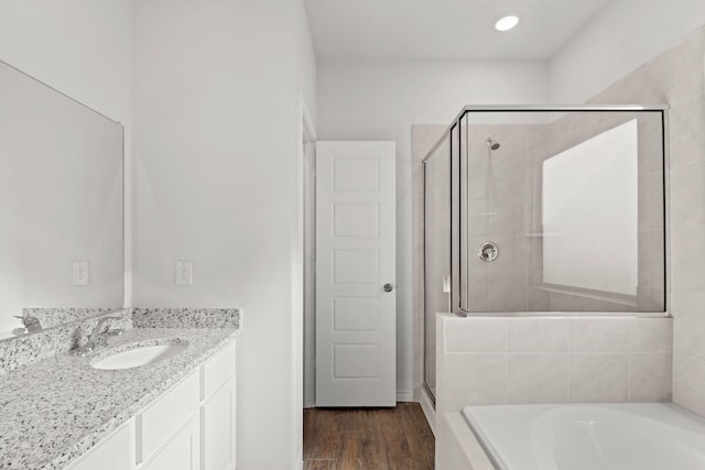 bathroom with hardwood / wood-style floors, separate shower and tub, and vanity