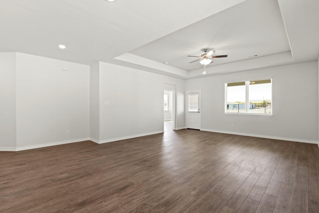 unfurnished room featuring ceiling fan, dark hardwood / wood-style floors, and a tray ceiling