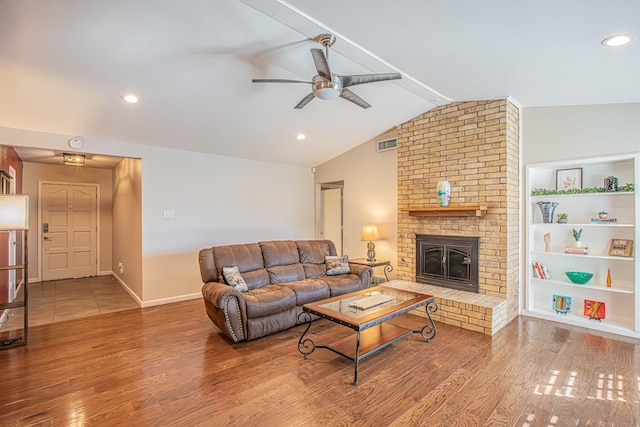 living room with hardwood / wood-style flooring, built in features, a brick fireplace, and vaulted ceiling with beams