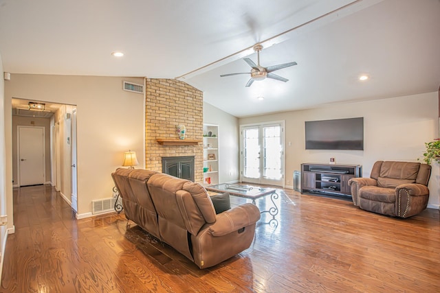 living room with a brick fireplace, lofted ceiling, built in features, and hardwood / wood-style flooring