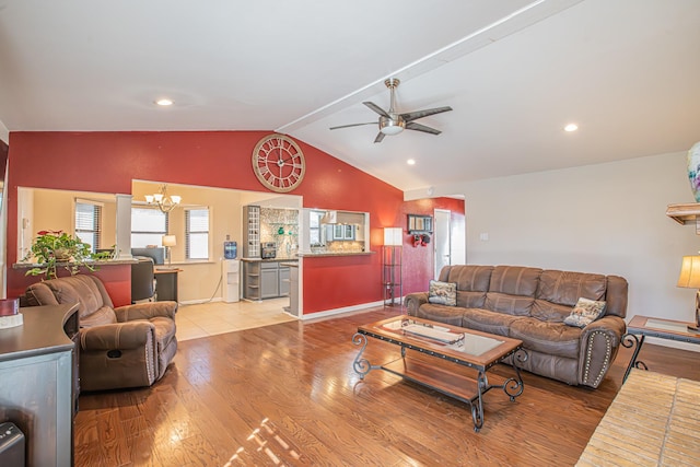 living room with lofted ceiling, ceiling fan with notable chandelier, and light hardwood / wood-style flooring