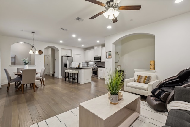 living room with ceiling fan with notable chandelier and light hardwood / wood-style floors