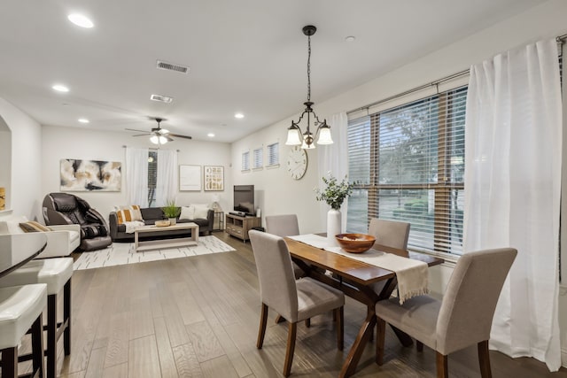 dining space featuring ceiling fan with notable chandelier and wood-type flooring