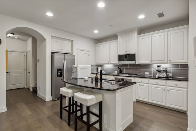 kitchen with white cabinets, appliances with stainless steel finishes, sink, and an island with sink