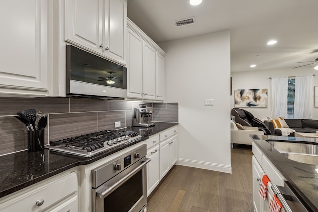 kitchen with dark stone counters, dark hardwood / wood-style flooring, stainless steel appliances, and white cabinetry