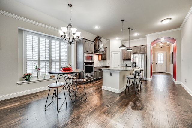 kitchen featuring stainless steel appliances, an island with sink, hanging light fixtures, a breakfast bar, and dark brown cabinets