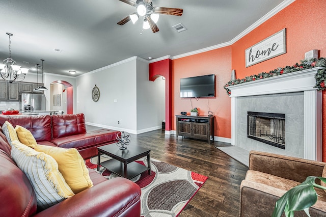 living room featuring a fireplace, dark wood-type flooring, ceiling fan with notable chandelier, and ornamental molding