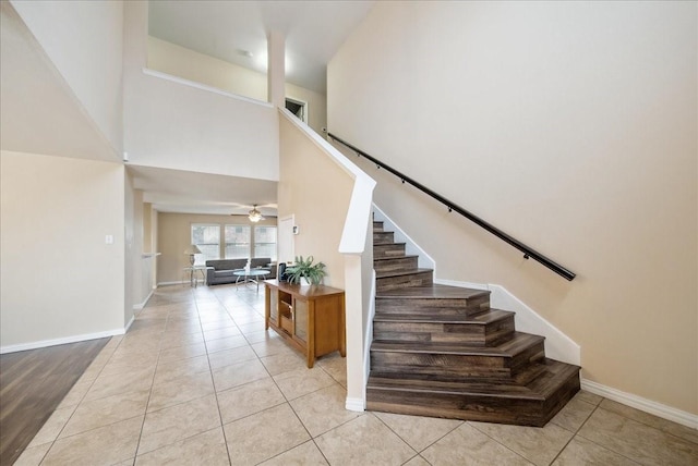 staircase with ceiling fan, a towering ceiling, and tile patterned floors