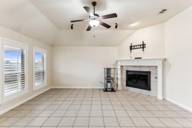 unfurnished living room featuring lofted ceiling, ceiling fan, a tile fireplace, and light tile patterned flooring