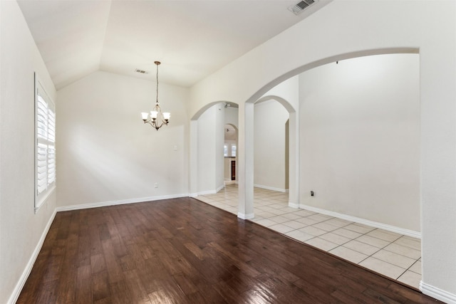 empty room with vaulted ceiling, an inviting chandelier, and light hardwood / wood-style flooring