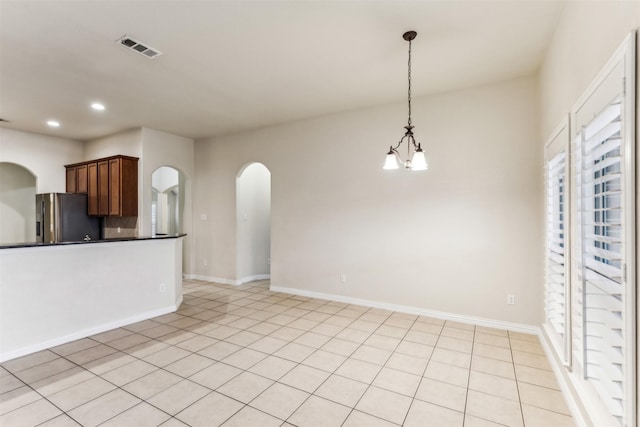 kitchen with an inviting chandelier, light tile patterned flooring, stainless steel fridge, and decorative light fixtures