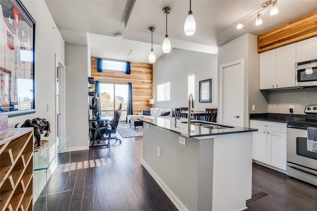 kitchen with appliances with stainless steel finishes, dark wood-type flooring, white cabinetry, hanging light fixtures, and wood walls