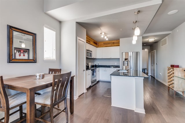 kitchen featuring a center island, sink, hanging light fixtures, stainless steel appliances, and white cabinets