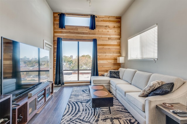 living room featuring dark hardwood / wood-style flooring, wood walls, and a towering ceiling