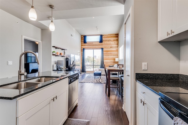 kitchen featuring sink, white cabinetry, stainless steel dishwasher, and wood walls