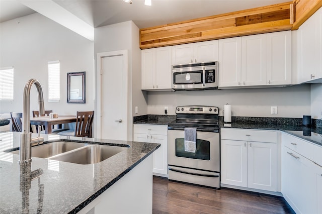 kitchen featuring white cabinets, appliances with stainless steel finishes, dark hardwood / wood-style flooring, and dark stone countertops