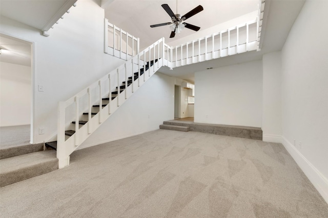 interior space with carpet floors, ceiling fan, and a towering ceiling