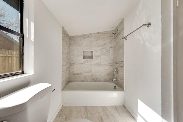 bathroom featuring toilet and tiled shower / bath combo