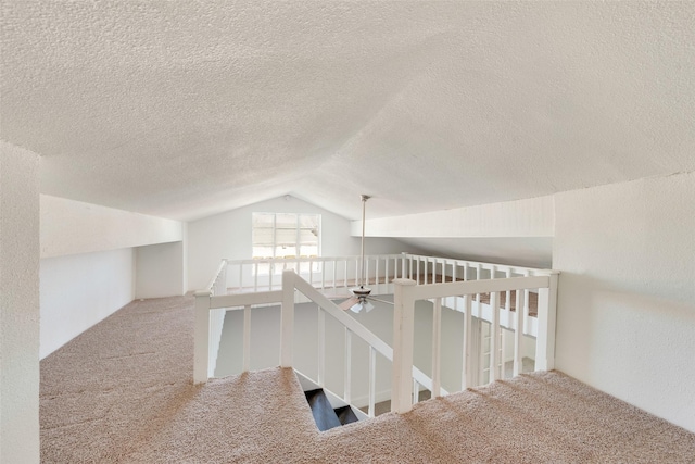 hallway featuring vaulted ceiling, a textured ceiling, and carpet flooring