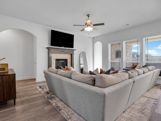 living room with hardwood / wood-style flooring, a tile fireplace, and ceiling fan