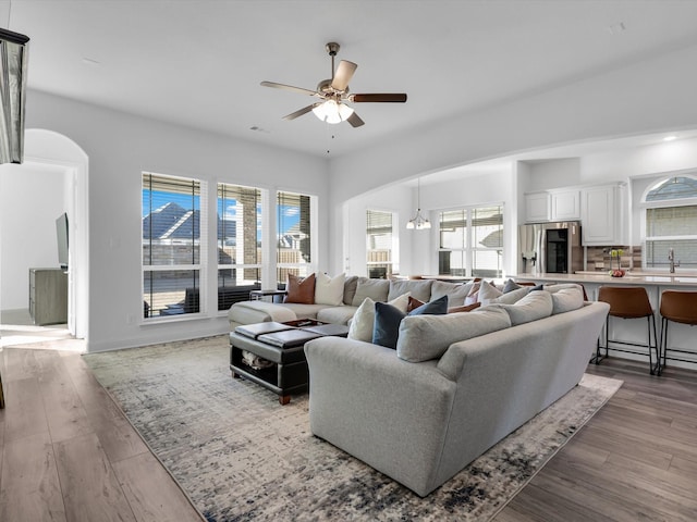 living room with sink, hardwood / wood-style floors, and ceiling fan with notable chandelier