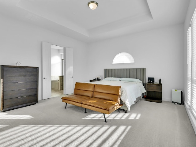 bedroom with light colored carpet, connected bathroom, and a raised ceiling