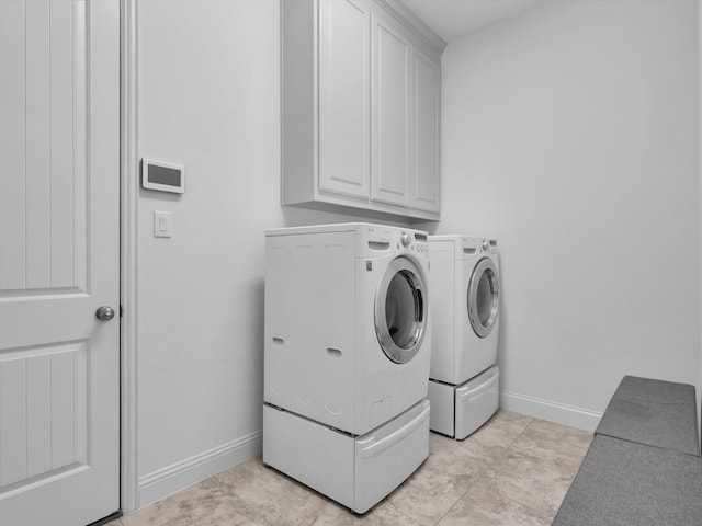 clothes washing area with light tile patterned flooring, cabinets, and washer and dryer