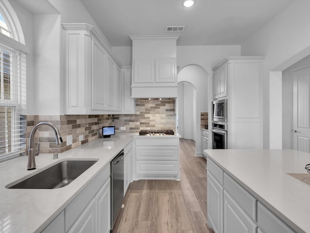 kitchen with decorative backsplash, sink, white cabinets, and stainless steel appliances