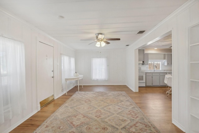 foyer featuring ceiling fan, light wood-type flooring, sink, and crown molding