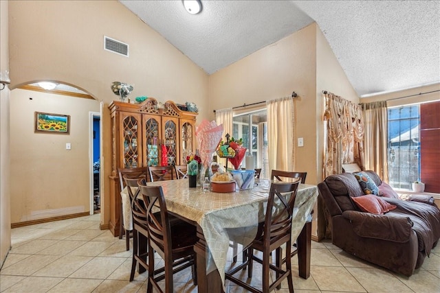 dining space featuring a textured ceiling, light tile patterned floors, and high vaulted ceiling