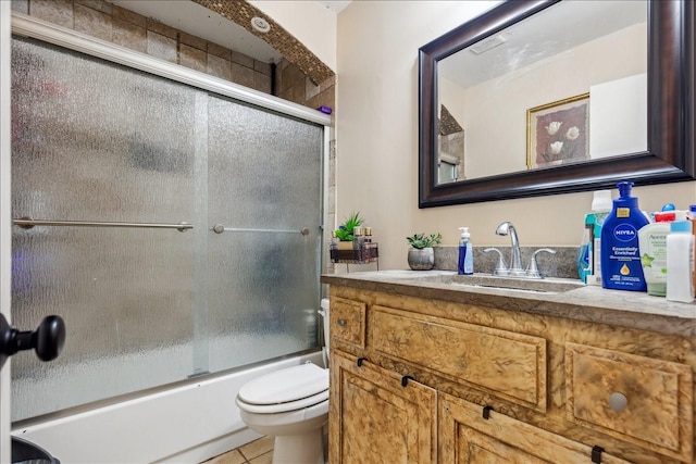 full bathroom featuring toilet, bath / shower combo with glass door, tile patterned flooring, and vanity