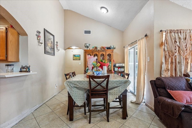 tiled dining area featuring vaulted ceiling and a textured ceiling