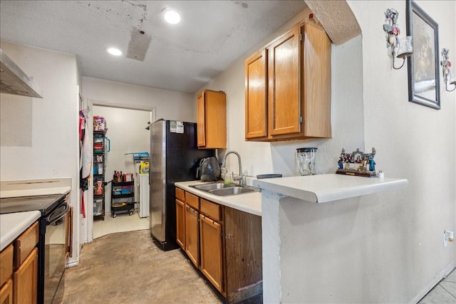 kitchen featuring wall chimney range hood, black electric range, stainless steel refrigerator, and sink