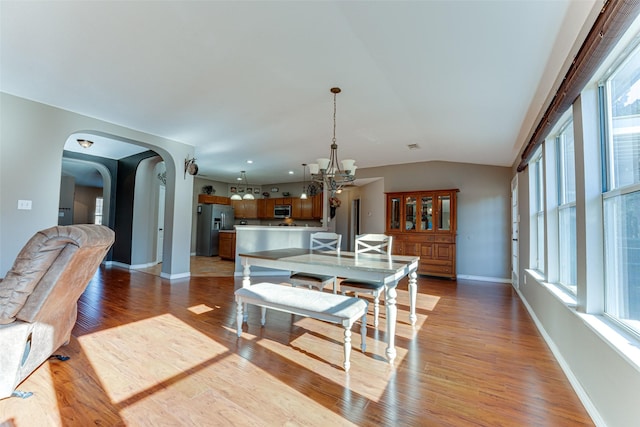 dining room with light hardwood / wood-style flooring, lofted ceiling, and a notable chandelier