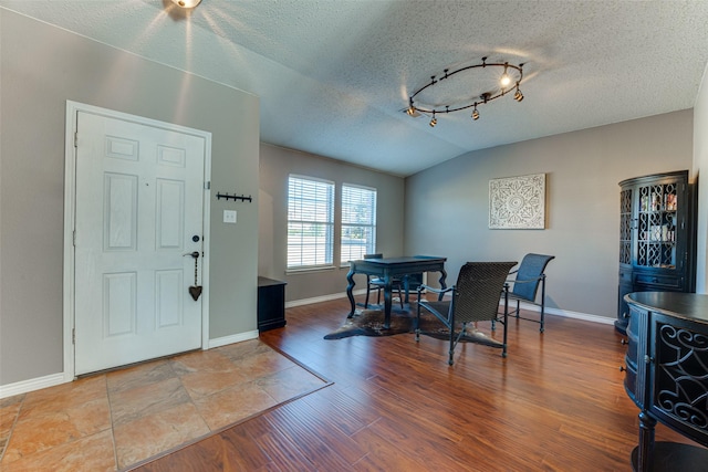 dining room featuring lofted ceiling, wood-type flooring, and a textured ceiling