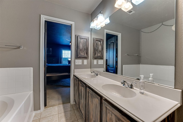 bathroom with tile patterned floors, a washtub, and vanity