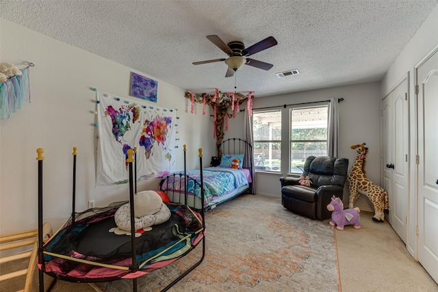 bedroom featuring ceiling fan, light colored carpet, and a textured ceiling