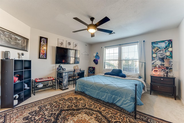 carpeted bedroom with ceiling fan and a textured ceiling