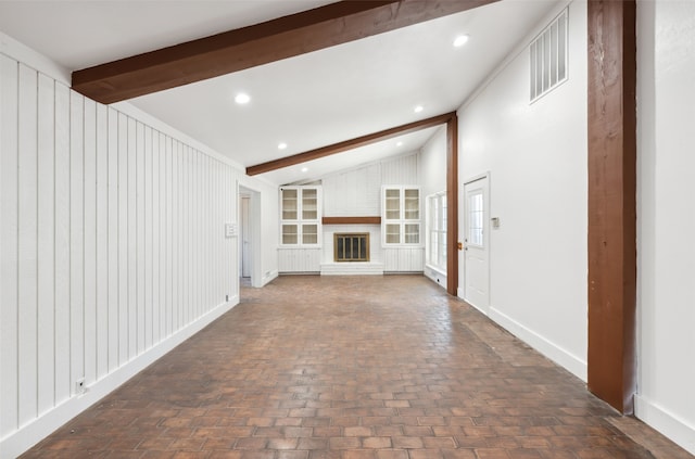 unfurnished living room with vaulted ceiling with beams and a brick fireplace