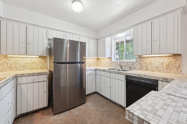 kitchen featuring sink, stainless steel fridge, backsplash, black dishwasher, and white cabinets